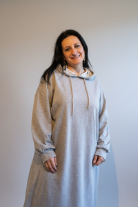 Grijze oversized hoodie gedragen door model in casual outfit, stijlvolle thuissfeer.