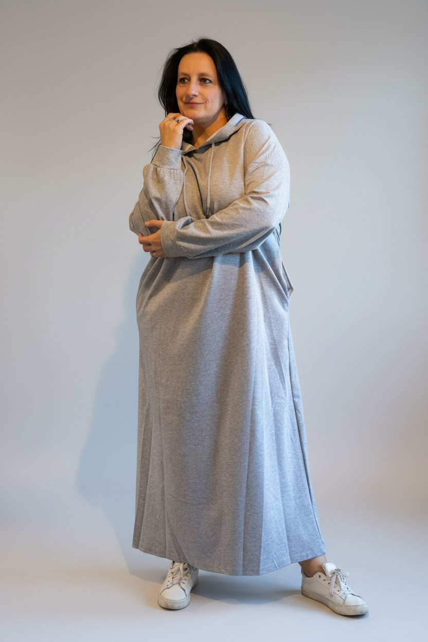 Grijze lange jurk met capuchon, casual stijl, model poseert in een interieur.