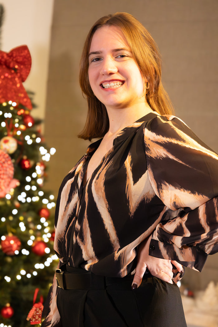 Model in een zwart met beige gestreepte blouse, casual chic, voor een feestelijke setting.
