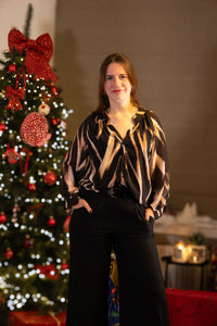 Gestreepte blouse in zwart en beige, gecombineerd met een zwarte broek, feestelijke uitstraling.