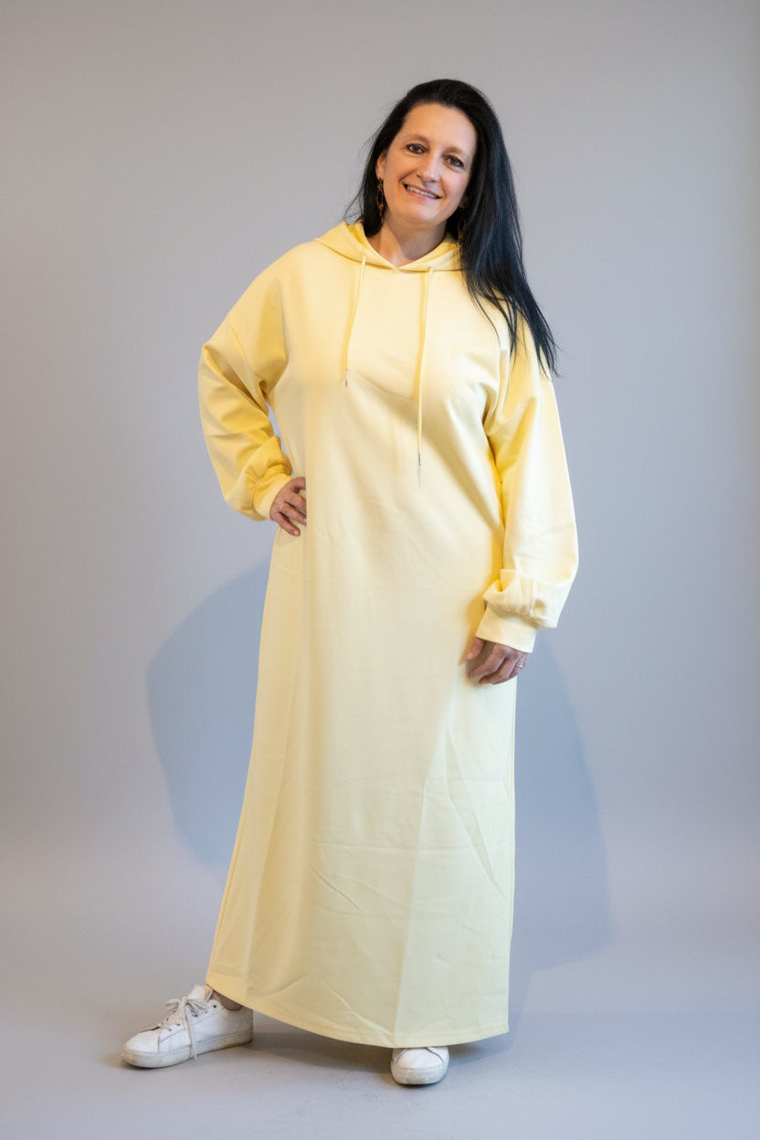 Geel lange hoodie zwangerschapskleding, casual stijl, gedragen door model met sneakers.