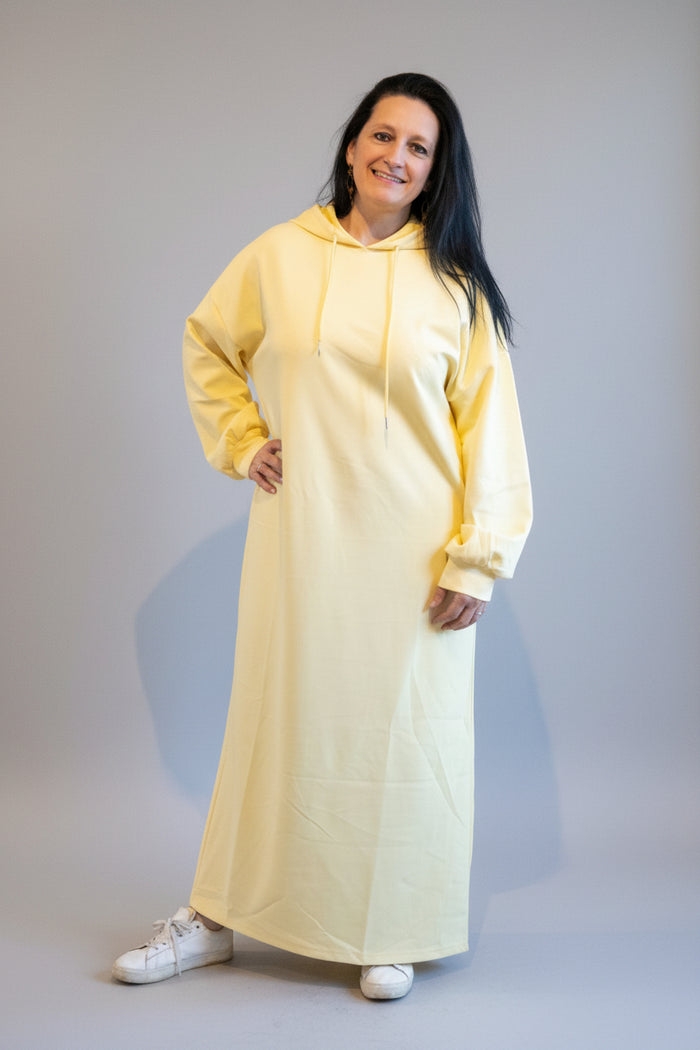 Geel lange hoodie zwangerschapskleding, casual stijl, gedragen door model met sneakers.