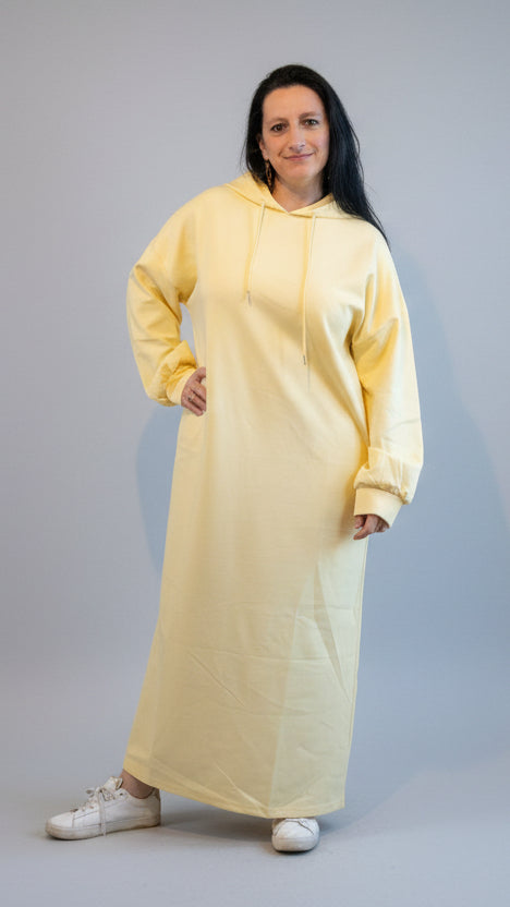 Lichtgele oversized hoodie jurk model in casual stijl, met witte sneakers.