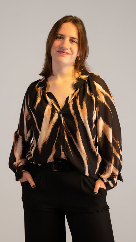 Zwarte blouse met abstracte print, casual chic stijl, model met handen in de zakken