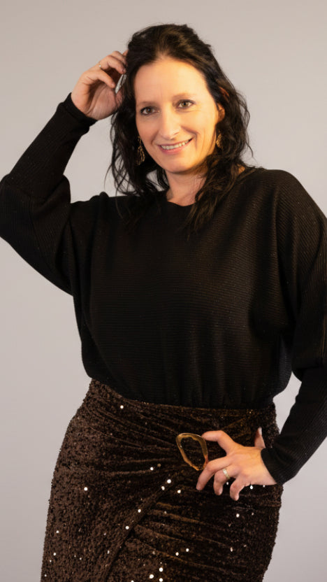 Zwart glanzend shirt met pofmouwen en een glinsterende bronskleurige rok, feestelijke look.