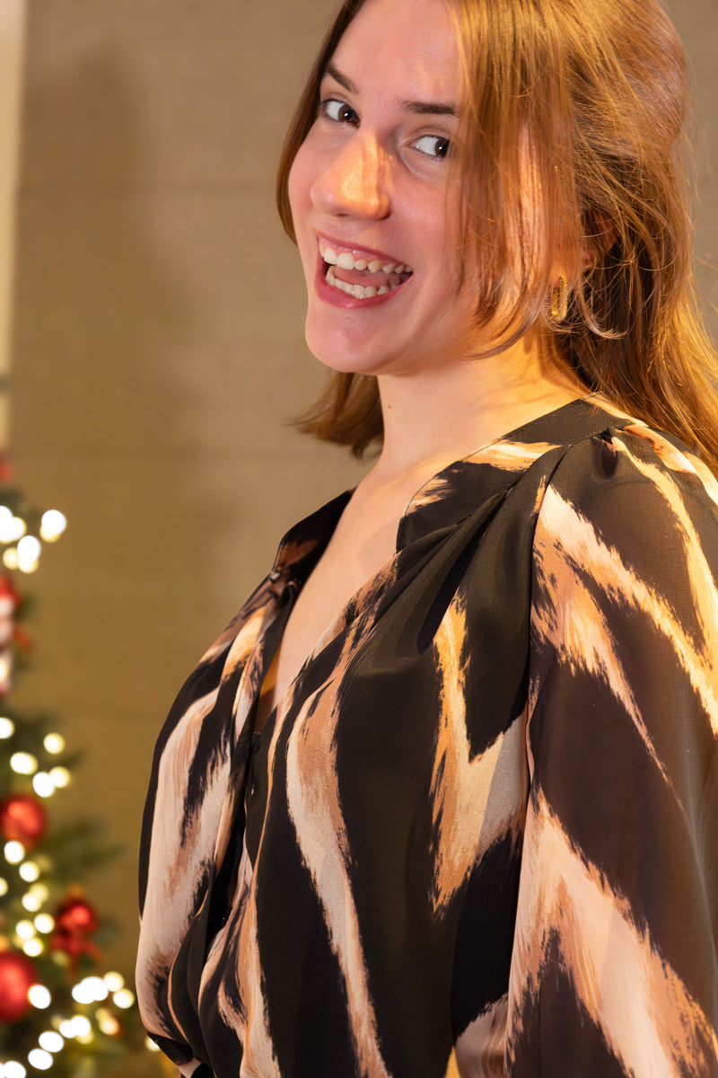 Zwart blouse met abstracte print, casual elegant, model glimlachend voor kerstdecoraties.