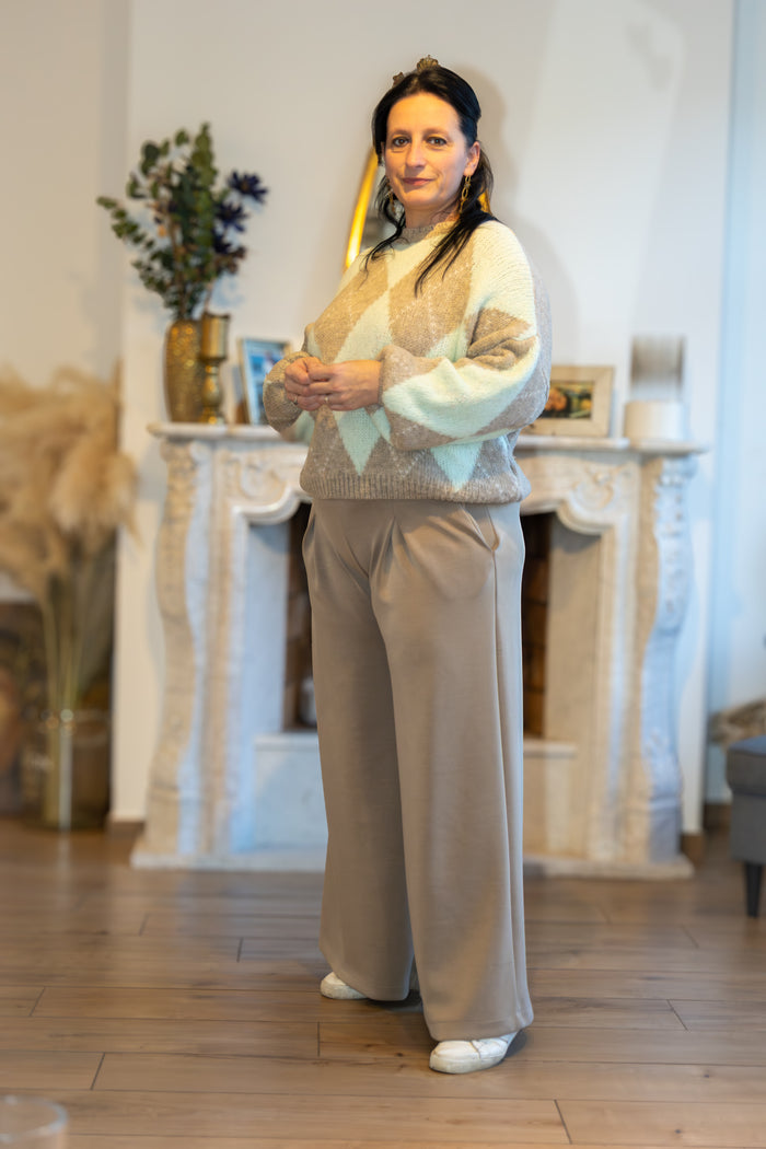 Stijlvolle, beige trui met groene en bruine ruitpatronen, gecombineerd met beige pantalon.