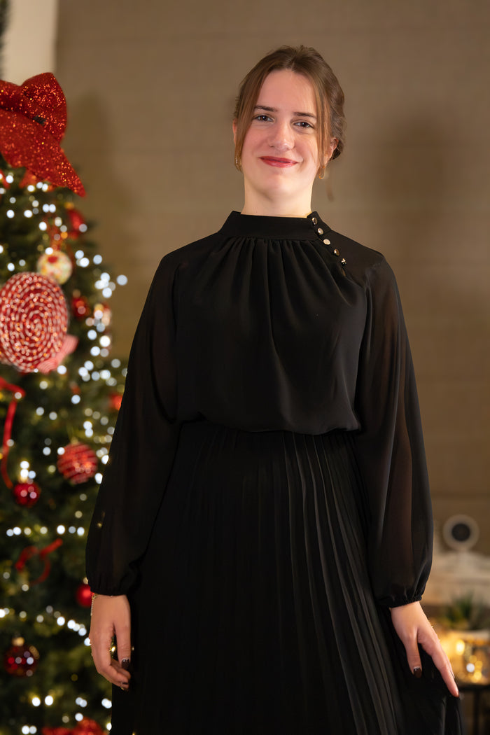 Zwarte blouse met hoge hals en plooien, elegant gedragen door een model voor een kerstboom.