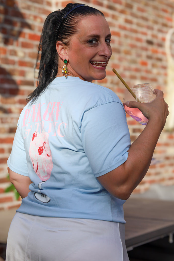 Lichtblauw T-shirt met zomerse “Pink Gin & Tonic” opdruk op de rug. Casual, comfy en ideaal voor aperitiefmomenten in stijl.