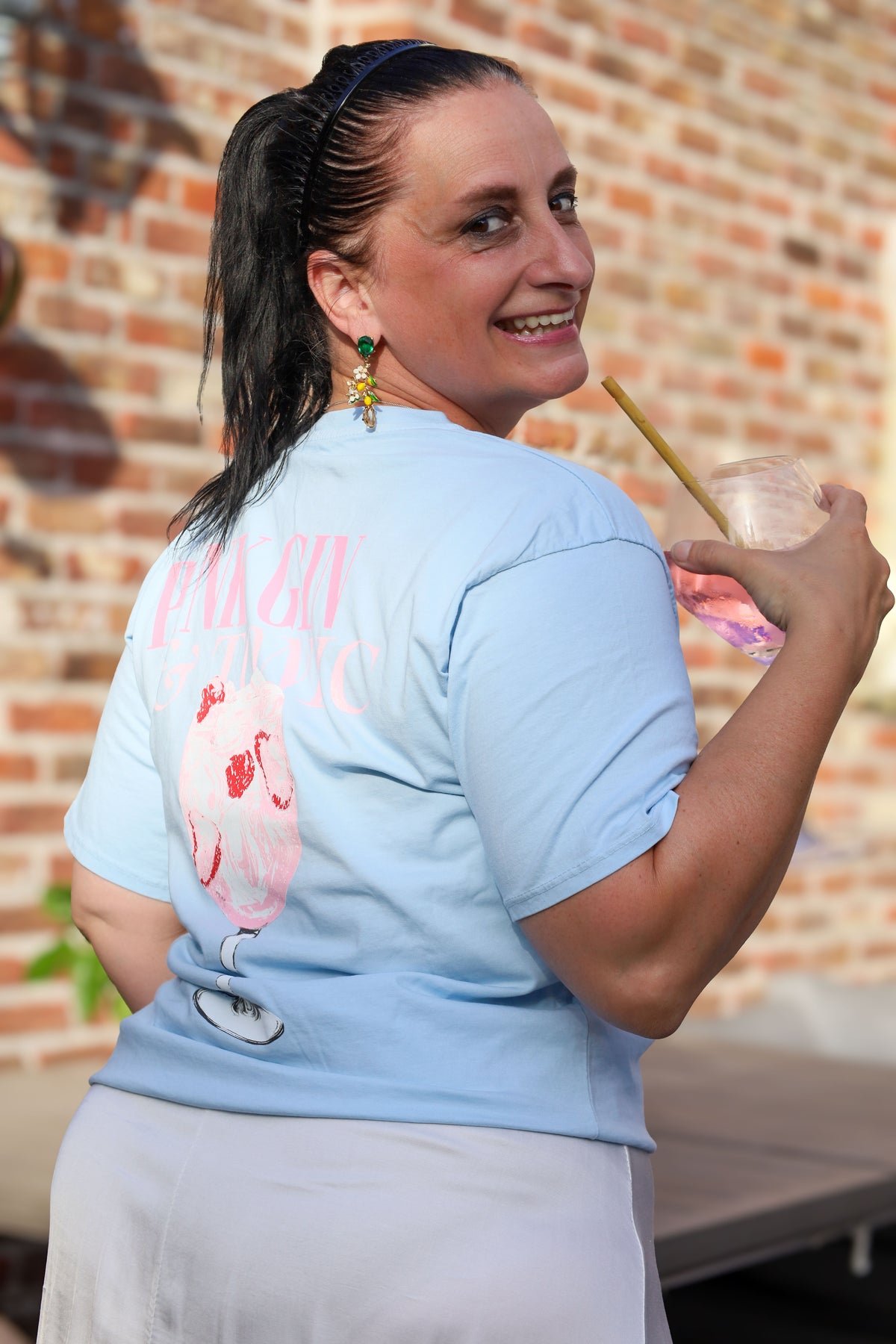 Lichtblauw T-shirt met zomerse “Pink Gin & Tonic” opdruk op de rug. Casual, comfy en ideaal voor aperitiefmomenten in stijl.