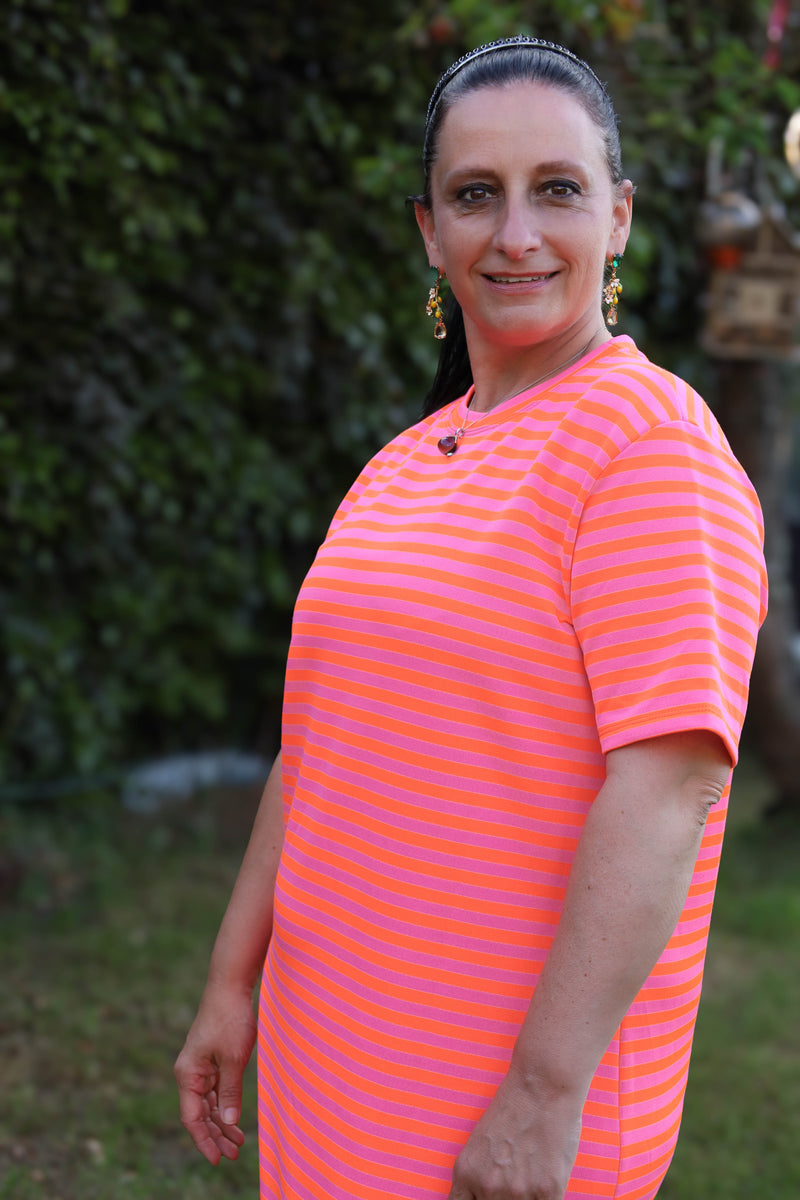 Lange T-shirtjurk met horizontale neonstrepen in roze en oranje. Comfortabel, speels en zomers.