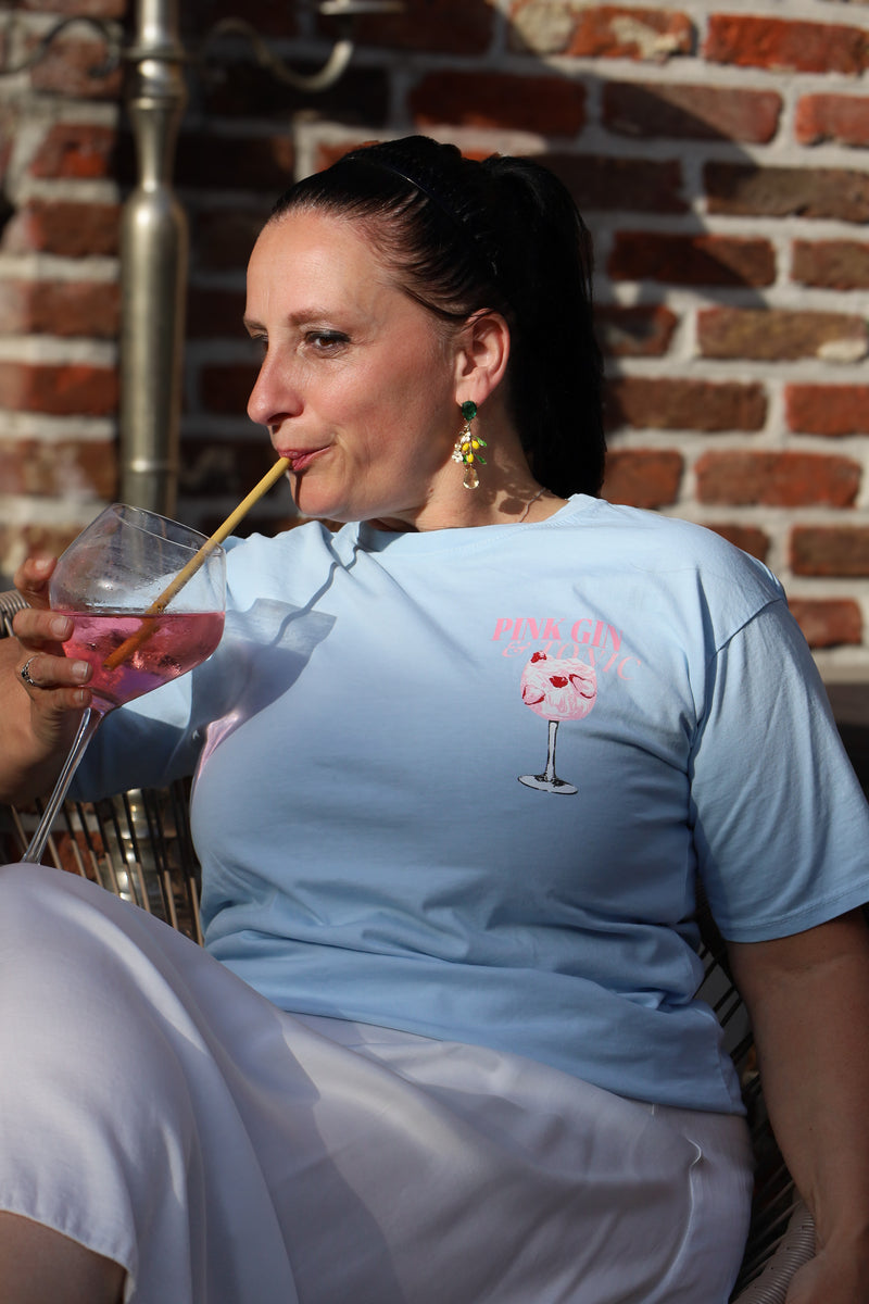 Lichtblauw T-shirt met zomerse “Pink Gin & Tonic” opdruk op de rug. Casual, comfy en ideaal voor aperitiefmomenten in stijl.