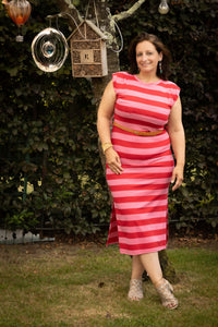 Gestreepte midi-jurk Terra di Siena gedragen in de natuur met een riem om de taille.