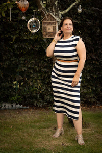 Vrouw in een gestreepte Terra Di Siena jurk marineblauw, poseert buiten met een elegante uitstraling.