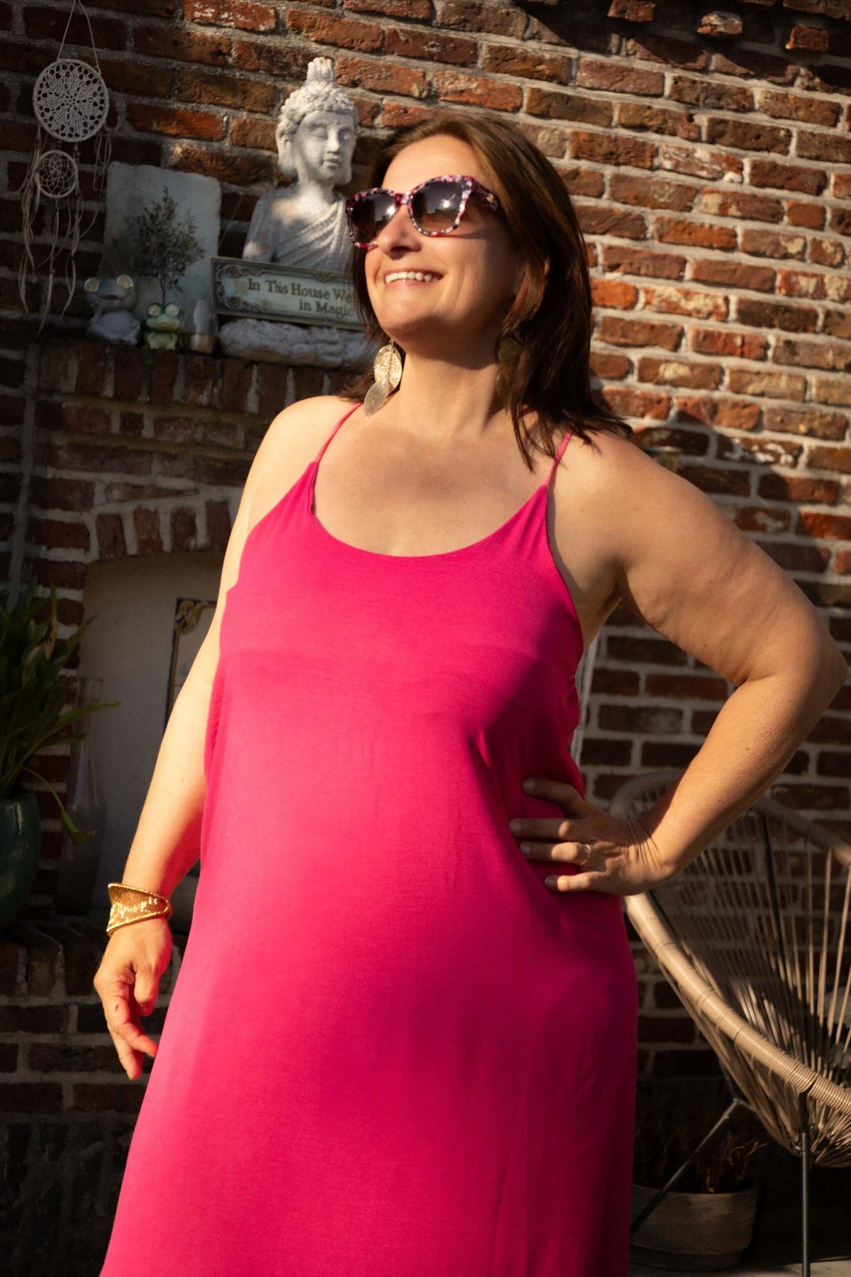 Model in Terra di Siena jurk fuchsia met zonnebril en zomerse uitstraling