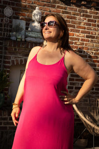 Model in Terra di Siena jurk fuchsia met zonnebril en zomerse uitstraling