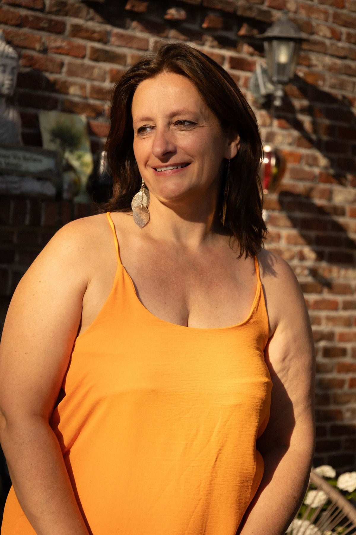 Vrouw in een oranje strapless maxi-jurk van Terra di Siena, perfect voor de zomer en warme dagen.