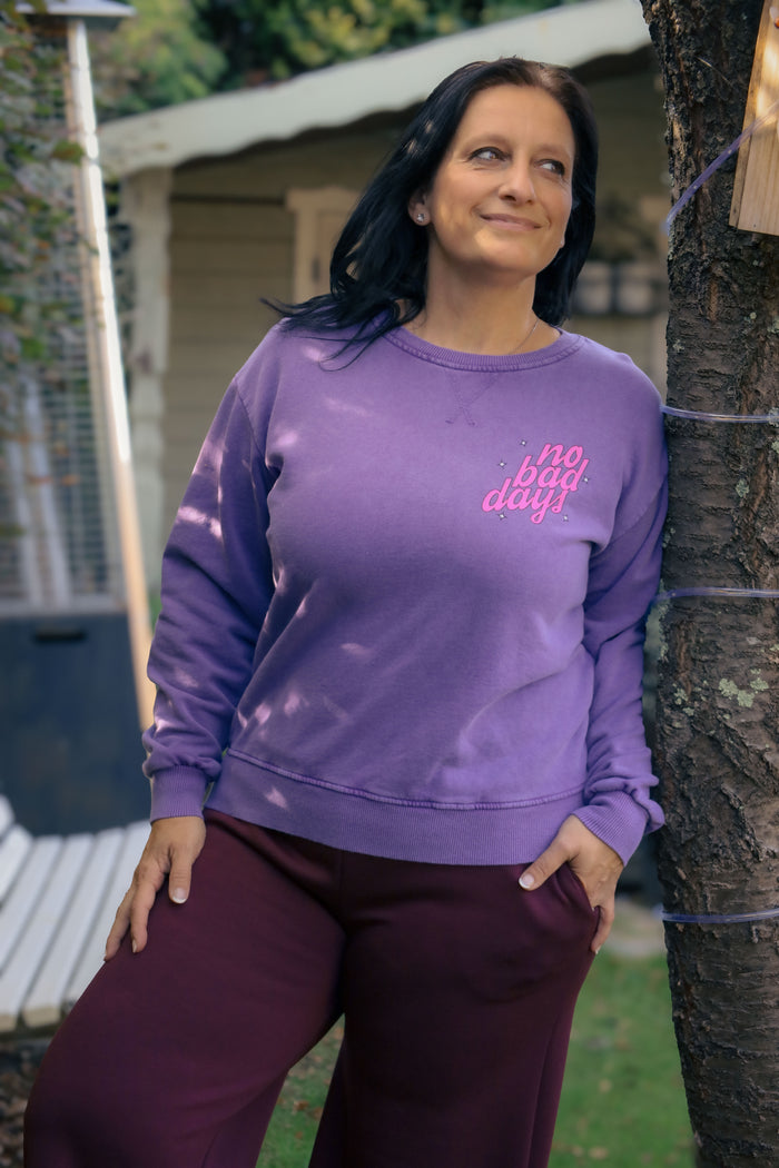 Vrouw draagt lila Dolci Giorni sweater met roze ‘No Bad Days’-print – casual damesmode bij She&Me Duffel.
