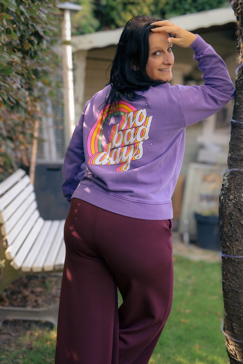 Vrouw draagt lila Dolci Giorni sweater met roze ‘No Bad Days’-print – casual damesmode bij She&Me Duffel.