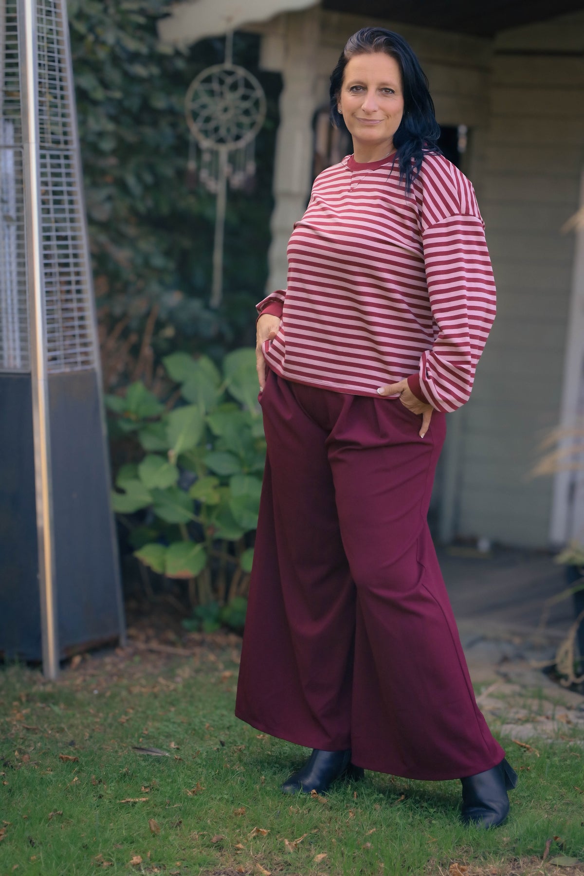 Vrouw draagt wijde bordeauxrode Dolci Giorni pantalon – elegante damesbroek bij She&Me Duffel.