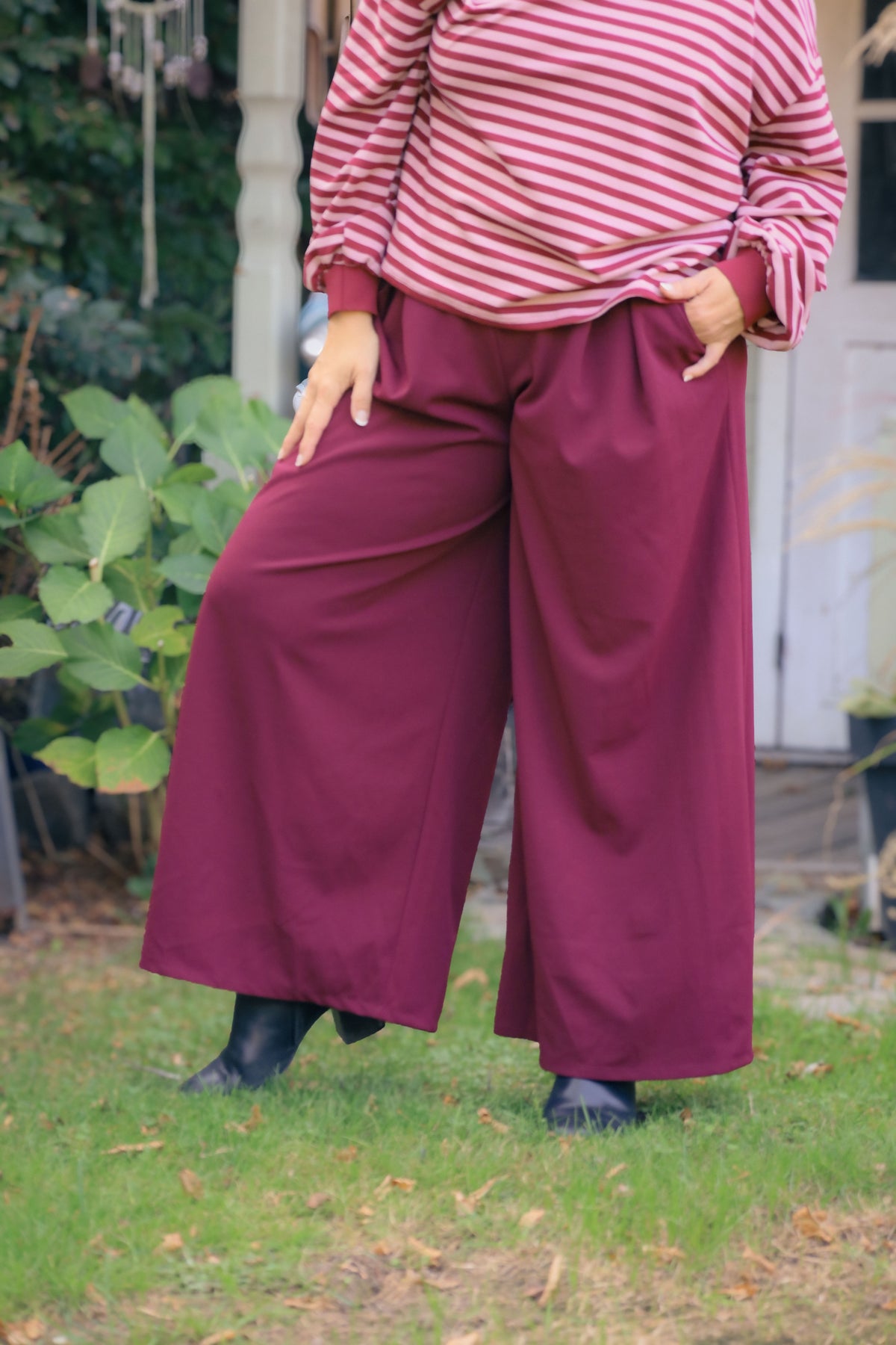 Vrouw draagt wijde bordeauxrode Dolci Giorni pantalon – elegante damesbroek bij She&Me Duffel.