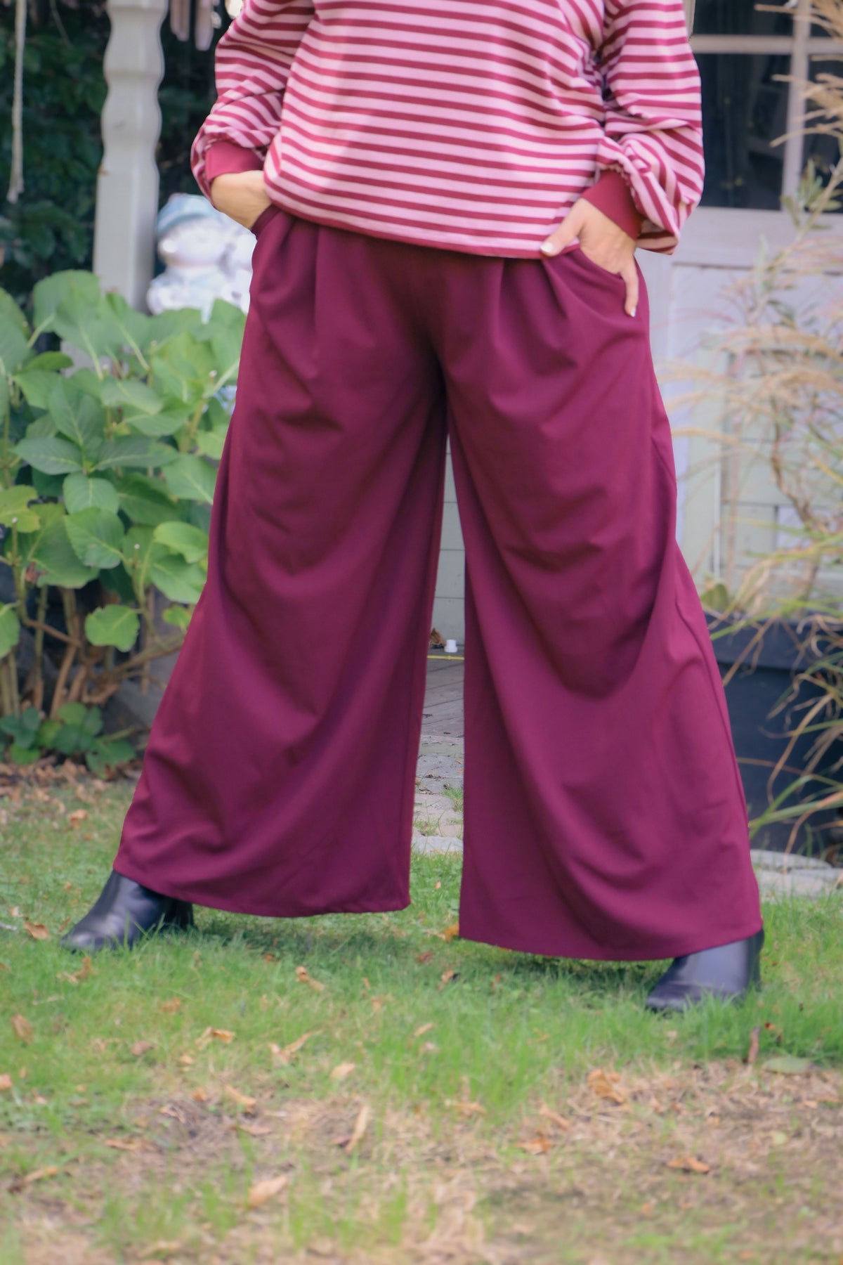 Vrouw draagt wijde bordeauxrode Dolci Giorni pantalon – elegante damesbroek bij She&Me Duffel.