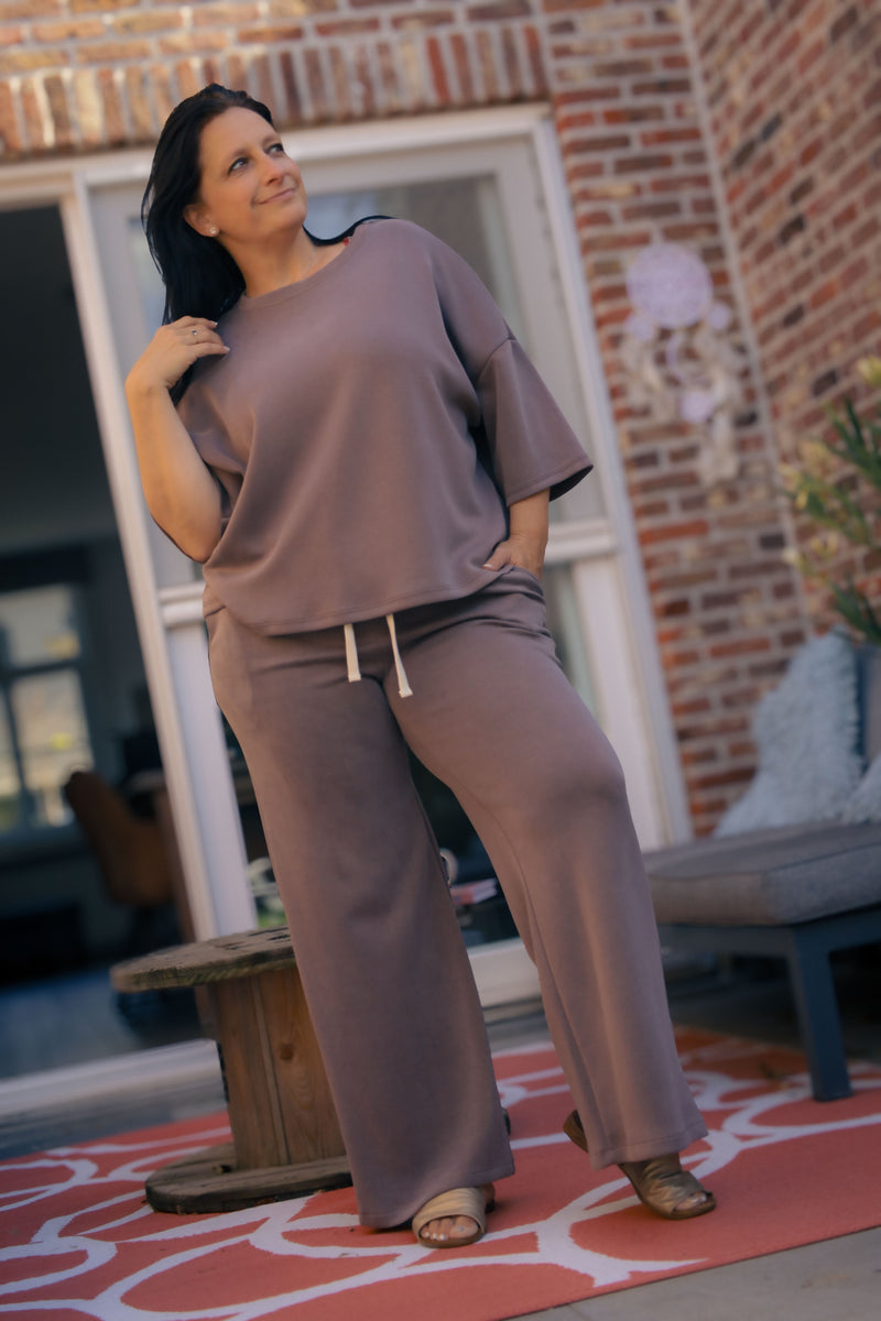 Vrouw poseert in taupe kleurige  Dolci Giorni set met losse top en broek – comfortabele damesmode bij She&Me Duffel.