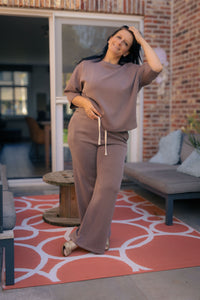 Vrouw poseert in taupe kleurige  Dolci Giorni set met losse top en broek – comfortabele damesmode bij She&Me Duffel.