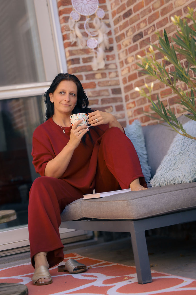 Vrouw poseert in bordeauxrode Dolci Giorni set met losse top en broek – comfortabele damesmode bij She&Me Duffel.
