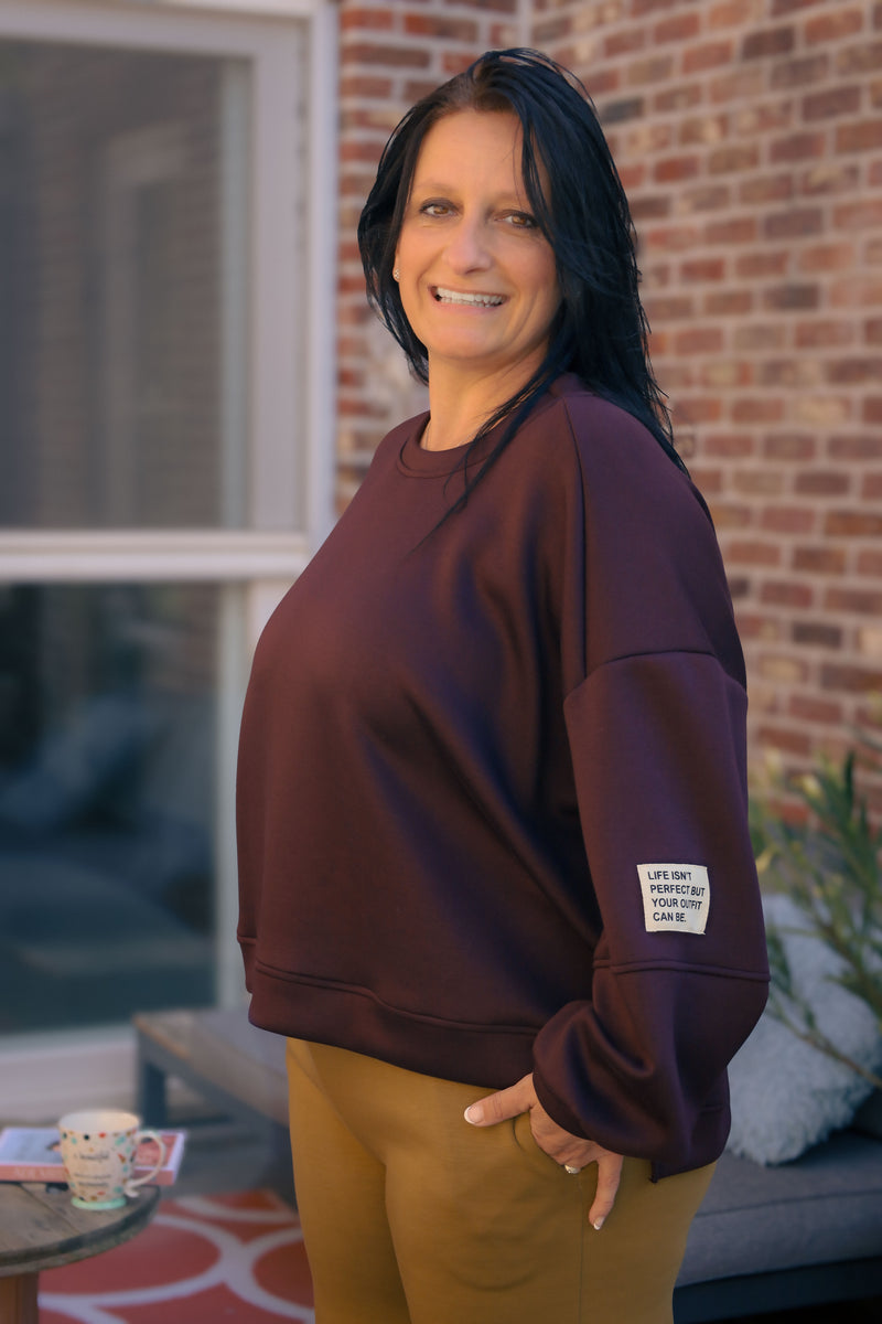 Vrouw draagt korte bordeauxrode Dolci Giorni trui met losse pasvorm – damesmode bij She&Me Duffel.