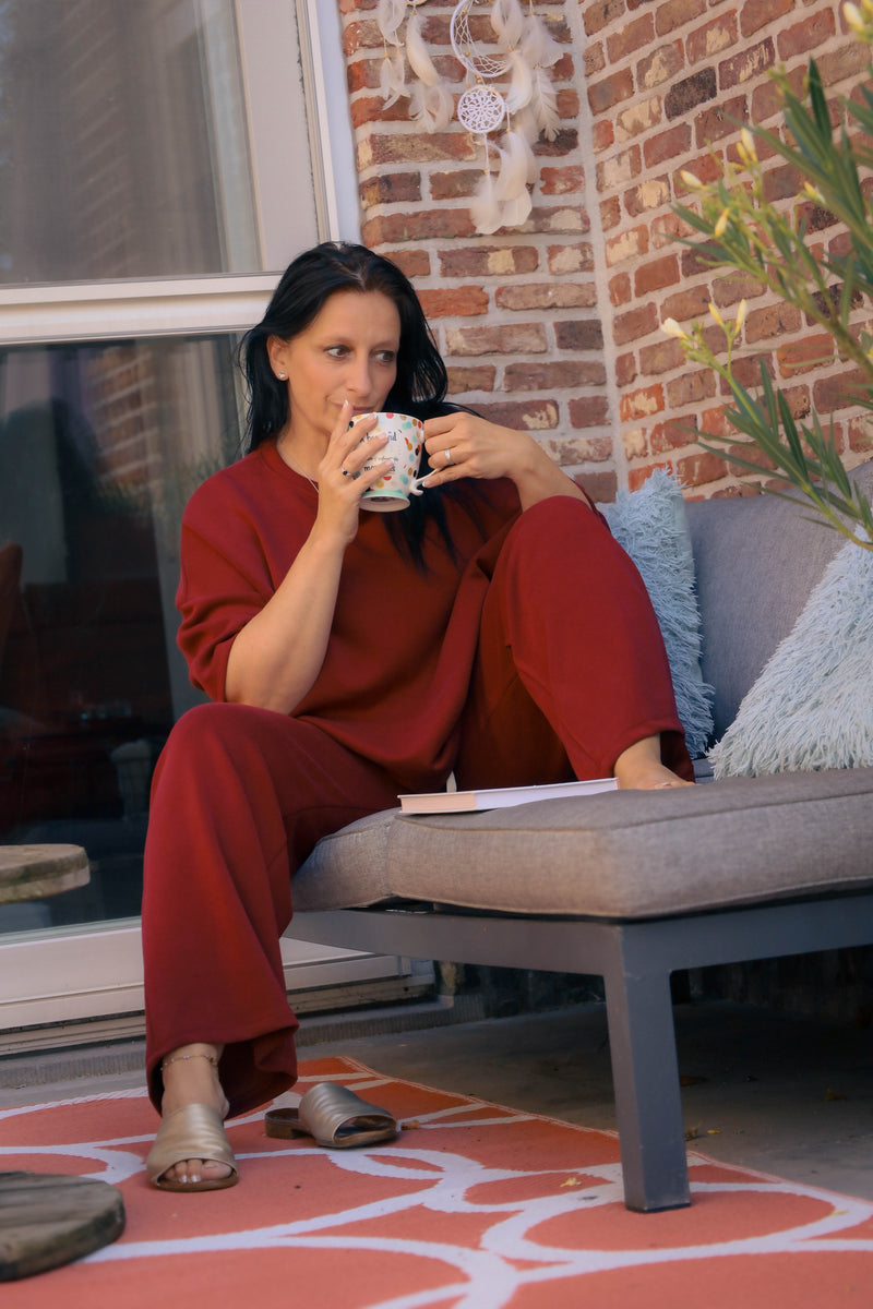 Vrouw poseert in bordeauxrode Dolci Giorni set met losse top en broek – comfortabele damesmode bij She&Me Duffel.