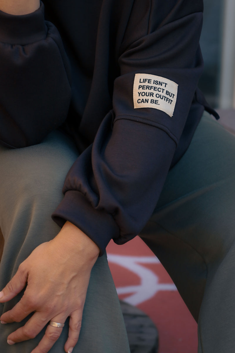 Vrouw draagt korte zwarte Dolci Giorni trui met losse pasvorm – damesmode bij She&Me Duffel.