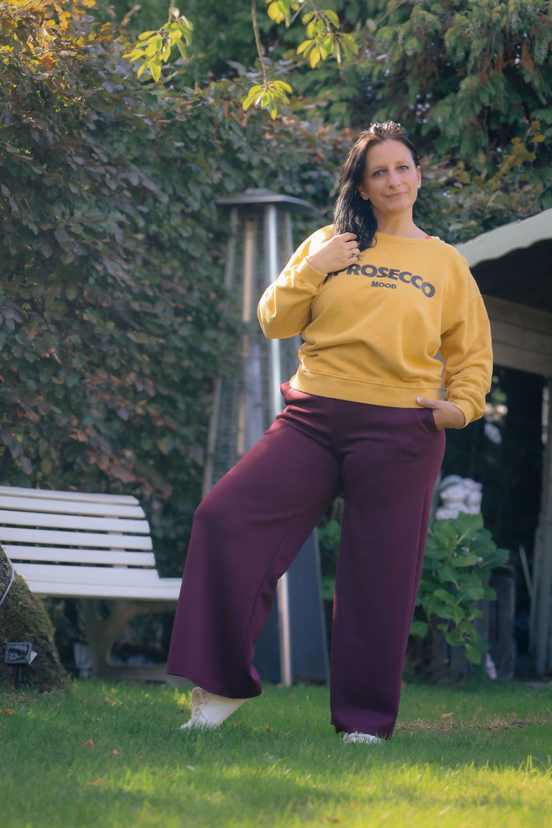 Vrouw draagt mosterdgele Dolci Giorni sweater met ‘Prosecco Mood’-print – comfortabele damesmode bij She&Me Duffel.