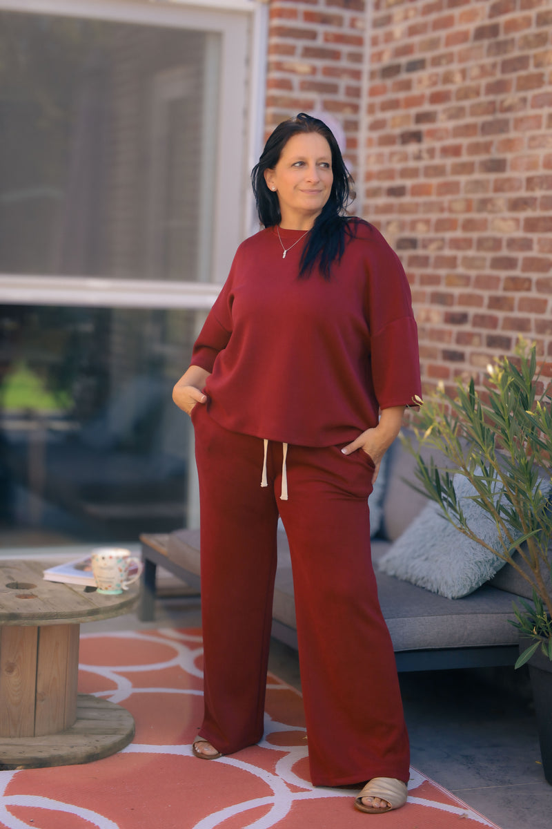 Vrouw poseert in bordeauxrode Dolci Giorni set met losse top en broek – comfortabele damesmode bij She&Me Duffel.