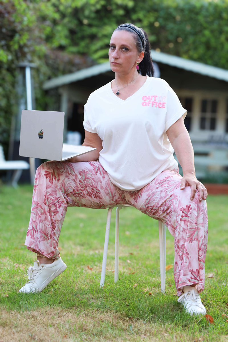 Wit V-hals T-shirt met roze “OUT OF OFFICE” badstofopdruk. Casual summer essential met een knipoog.

