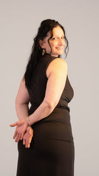 Zwarte jurk gedragen door vrouw, feestelijke uitstraling met kerstdecoraties op de achtergrond.