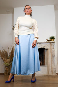 Vrouw met lichtblauwe midi-rok en blauwe hakken in een elegante pose