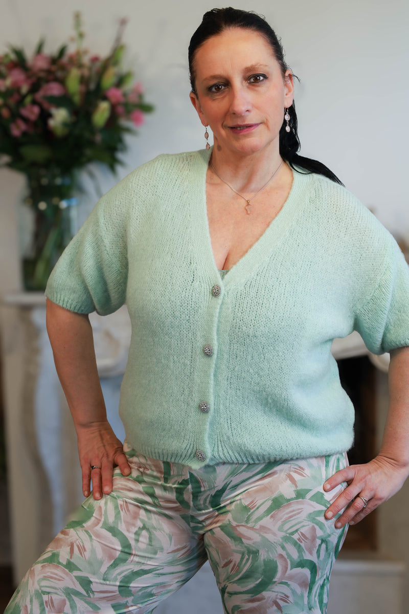 Model draagt mintgroene zachte gilet met knopen op een losse printbroek