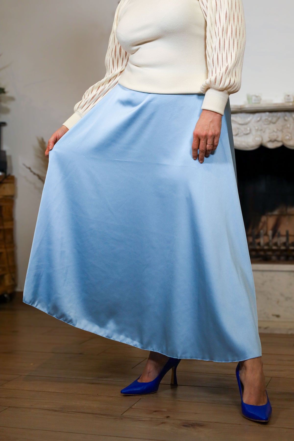 Vrouw met lichtblauwe midi-rok en blauwe hakken in een elegante pose