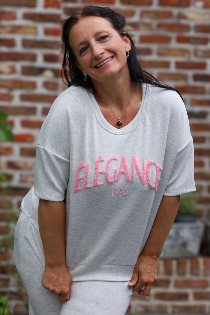 Vrouw draagt lichtgrijze T-shirt “Élégance 1990” uit de La Dolce Vita collectie van She & Me – damesmode Duffel